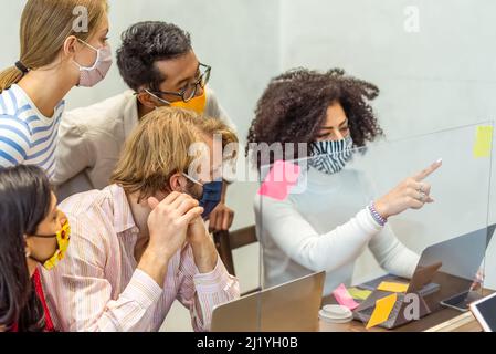 Multiracial group of young startup working together with protective face mask, co working space and healthy care in small business office, the new nor Stock Photo