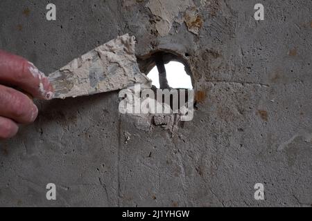 Fixing hole on the wall, spreading plaster using trowel Stock Photo