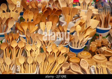 Wooden spoons, forks and other kitchen tools are on a local market display. Wooden tools are hand-graven. Stock Photo