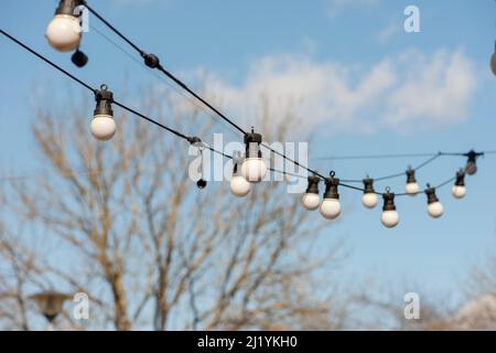 Garland of light bulbs on a blue sky background. Stock Photo