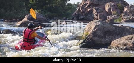A man rowing inflatable packraft on whitewater of mountain river. Concept: summer extreme water sport, active rest, extreme rafting. Stock Photo