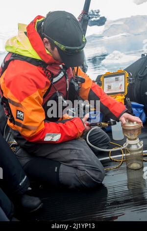Guests from Antarctic cruise ship take part in citizen scientists project, Collecting plankton samples, ocean temperature and water clarity off Danco Stock Photo