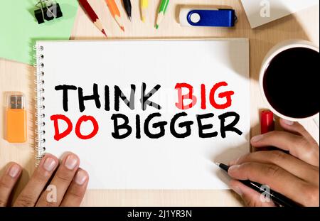 Think Big, Do Bigger Motivation quote written on a note paper. Stock Photo