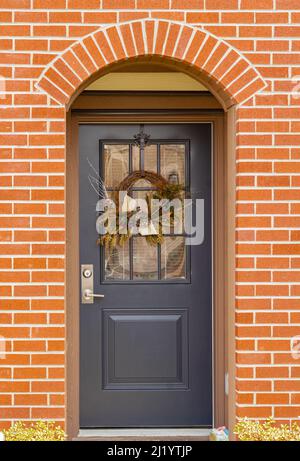 Red brick wall with nice brown door. Exterior of a house. Entrance of a nice single family house. Nobody, selective focus, street photo Stock Photo