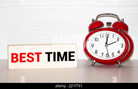 best TIME written in a notebook near a red alarm clock. Stock Photo