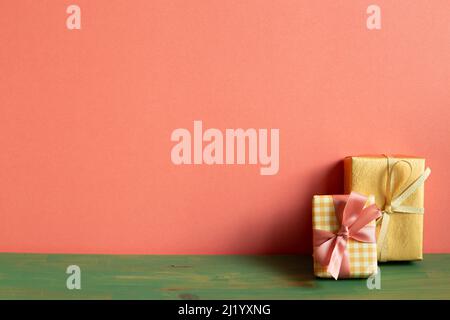 Yellow and gold gift box on green wooden table. pink wall background. copy space Stock Photo