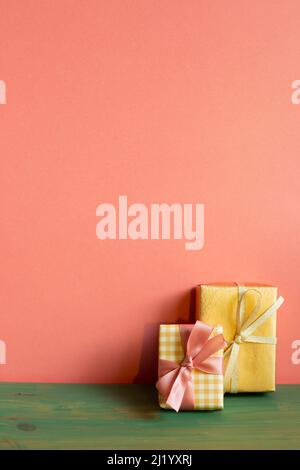 Yellow and gold gift box on green wooden table. pink wall background. copy space Stock Photo