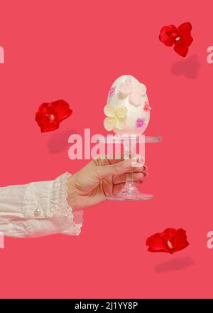 Creative Easter abstract concept. A female hand holds a large white Easter egg. The egg is decorated with pastel flowers. Red flowers with shadows in Stock Photo
