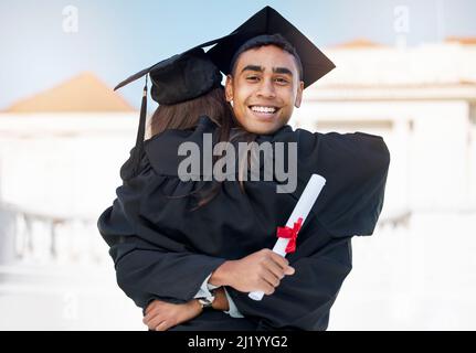 I did it with tons of support from everyone. Portrait of a young man hugging his friend on graduation day. Stock Photo