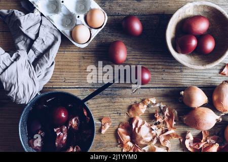 Dyed Easter eggs painted with natural dye onion on rustic wooden background. Process of dyeing eggs with natural paints for Easter. Natural ecological Stock Photo