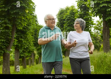 Active healthy cheerful smiling senior retired couple jogging in green park Stock Photo