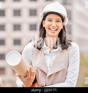 Ive got the plans in hand. Cropped portrait of an attractive young female engineer standing with blueprints on a construction site. Stock Photo