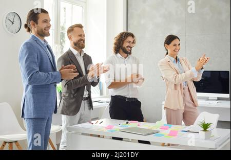Smiling multiethnic employees applaud congratulate coworker with success Stock Photo