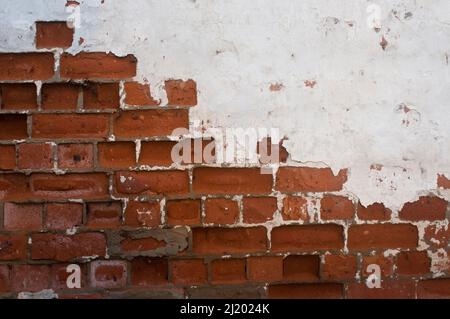 WHite paint on brick. White paint and plaster eroded from a brick wall in an abandonded building.