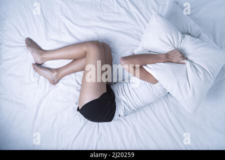 Top view of woman with depression, insomnia or psychological problems lying on the bed Stock Photo