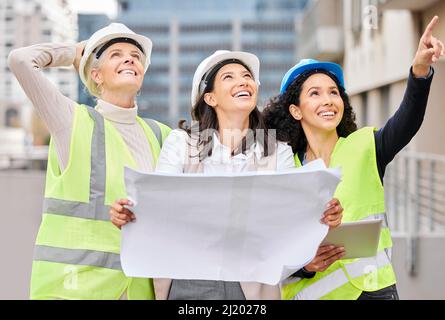 Watching their plan unfold. Cropped shot of three attractive female engineers reading a blueprint while working on a construction site. Stock Photo