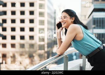 Staying confident and relaxed gets the job done. Shot of an attractive young businesswoman standing alone outside and using her cellphone. Stock Photo
