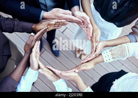Satisfaction lies in the effort. Shot of a group of unrecognizable businesspeople forming a circle with their hands outside. Stock Photo