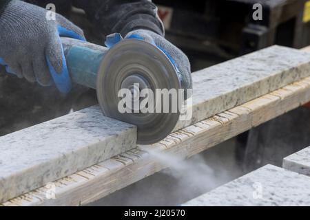Dust while grinding close-up of worker cutting granite plate with grinder. Stock Photo