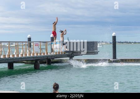 Tauranga New Zealand March 26 2022;boys enjoy jumping of pier and diving platform on city waterfront adjacent to harbour steps. Stock Photo