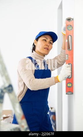 Builder Using Level Woman builder using building level measures the vertical of wall Stock ...
