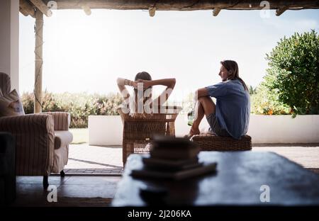Theres nothing better than chilling with you all day. Rearview shot of a young couple chilling outside on the veranda at home. Stock Photo