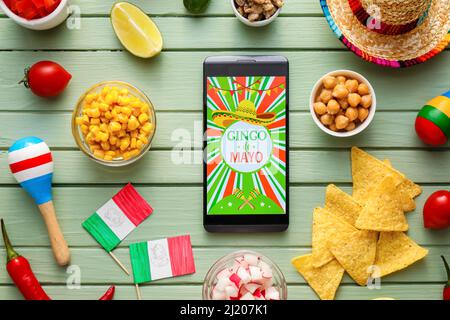 Traditional Mexican food with maracas and mobile phone on color