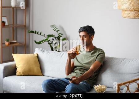 Handsome man drinking beer while watching TV at home Stock Photo