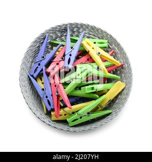 Wicker bowl with plastic clothes pins on white background Stock Photo