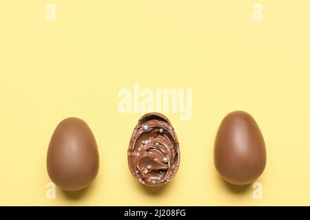 Delicious chocolate eggs with paste filling on yellow background Stock Photo