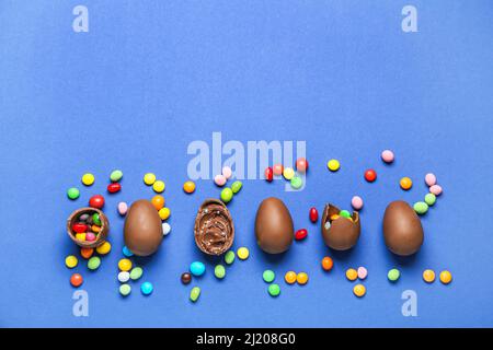 Delicious chocolate eggs with different fillings on blue background Stock Photo