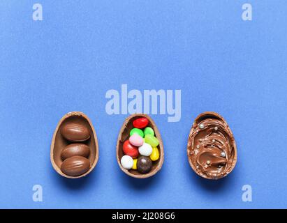 Delicious chocolate eggs with different fillings on blue background Stock Photo