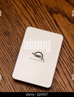 A silver OWC Envoy Pro Elektron 1 TB SSD portable storage device isolated on an oak desk Stock Photo