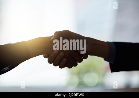 Business is all about formalities. Cropped shot of two silhouetted businesspeople shaking hands in the office. Stock Photo