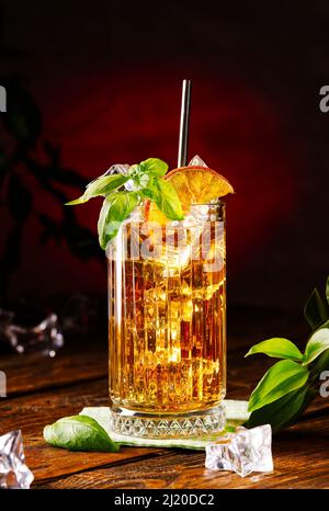 Glass of long island ice tea cocktail decorated with mint. Cuba Libre low key Stock Photo