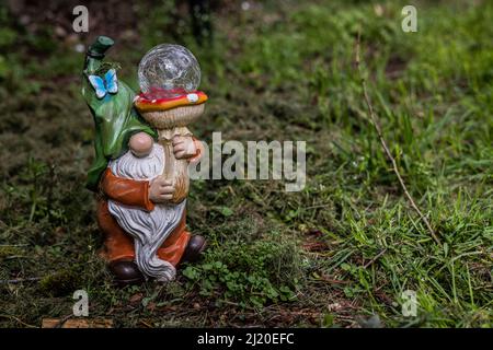 Little man with beard holding up mushroom rod that is solar light in yard. Stock Photo