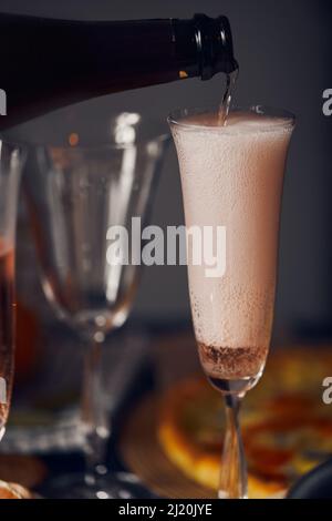 Champagne is poured from a bottle into a glass of retro style. Vertical photo. Stock Photo