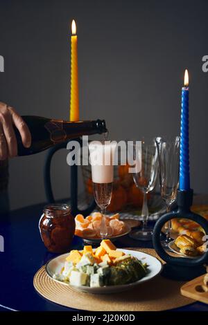 Champagne poured into a glass in retro style, the concept of a holiday, set table for a date. Vertical photo. Stock Photo