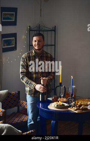 Man opens champagne, the concept of a holiday, a table set for a date. Vertical photo. Stock Photo