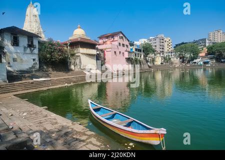 A small rowing boat is anchored in Banganga Tank, a sacred Hindu spot  surrounded by several Hindu temples, in Walkeshwar area, Mumbai, India Stock Photo