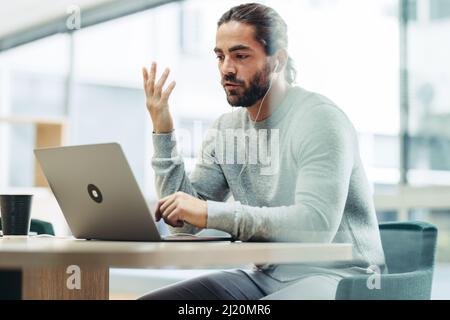 businessman having a discussion with his associates during an online meeting. Modern businessman attending a video conference while working remotely i Stock Photo