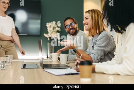 Cheerful businesswoman having a discussion with her colleagues in a boardroom. Group of happy businesspeople sharing ideas during a meeting in a moder Stock Photo