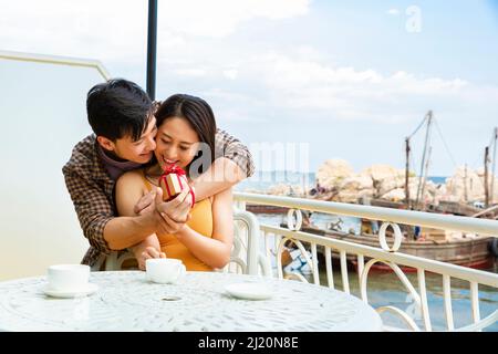 Fiance who gives fiancee a surprise engagement gift at a restaurant near a fishing boat dock - stock photo Stock Photo
