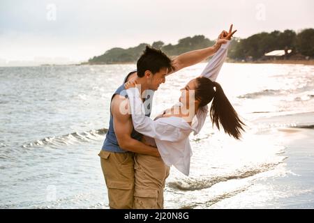 Embracing young lovers dancing on the beach - stock photo Stock Photo