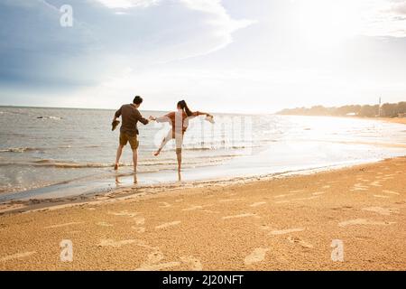 Barefoot young lovers treading water on the beach - stock photo Stock Photo