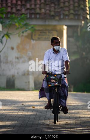 Galle, Sri Lanka - 02 26 2022: Concept of everyday life in Sri Lanka, Elderly ride a bicycle early in the morning, Stock Photo