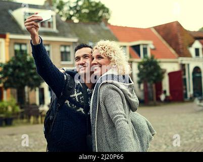 Taking a few selfies in a foreign city. Cropped shot of a young couple taking selfies while on vacation. Stock Photo