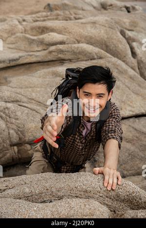 Climber reaching out to his partner for help - stock photo Stock Photo