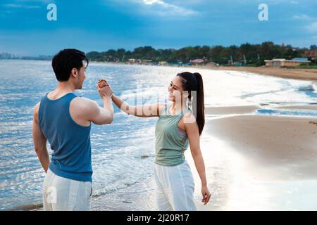 Young couple high-fiving on the beach - stock photo Stock Photo