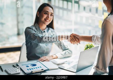 Young asian business people shaking hands in the office. Finishing successful meeting. Stock Photo